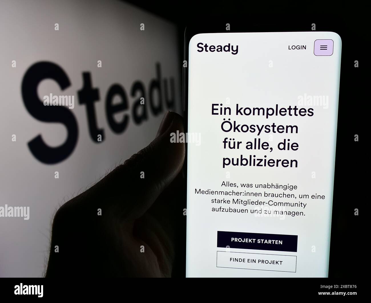 Personne tenant un smartphone avec le site web de la société allemande de crowdfunding Steady Media GmbH devant le logo. Concentrez-vous sur le centre de l'écran du téléphone. Banque D'Images