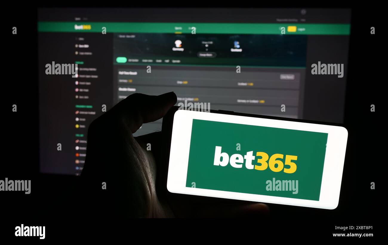 Personne tenant le téléphone portable avec le logo de la société britannique de Paris sportifs Bet365 en face de la page Web de l'entreprise. Concentrez-vous sur l'affichage du téléphone. Banque D'Images