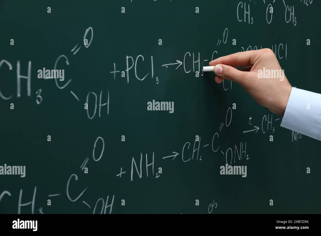 Professeur écrivant des formules chimiques avec de la craie sur un tableau vert, gros plan Banque D'Images