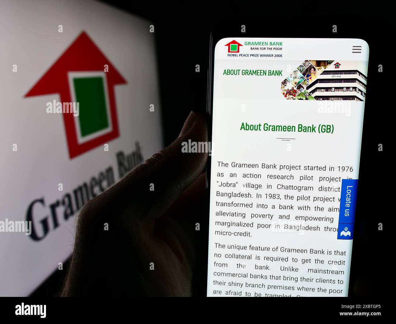 Personne tenant un téléphone portable avec la page Web de la société de microfinance bangladaise Grameen Bank devant le logo. Concentrez-vous sur le centre de l'écran du téléphone. Banque D'Images