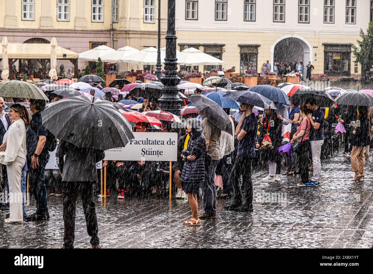 Sibiu City, Roumanie - 11 juin 2024. Cérémonie de remise des diplômes où les étudiants jettent leurs casquettes en l'air sous une forte pluie Banque D'Images