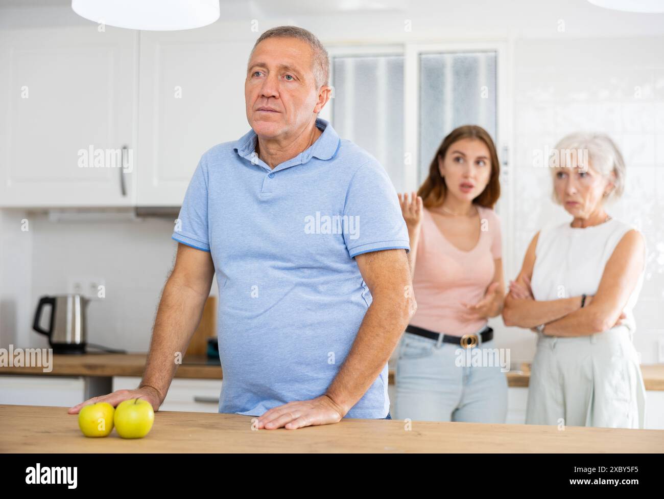 Père bouleversé debout dans la cuisine séparément, conflit familial Banque D'Images
