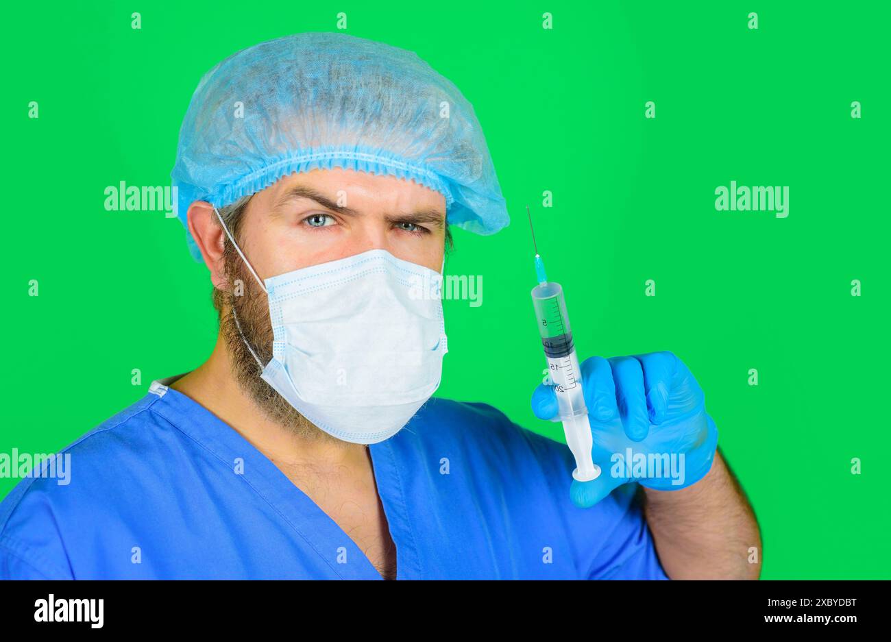 Vaccination et traitement. Médecin sérieux en uniforme, chapeau chirurgical et masque facial tient seringue avec vaccin. Infirmier ou médecin en gants de caoutchouc Banque D'Images