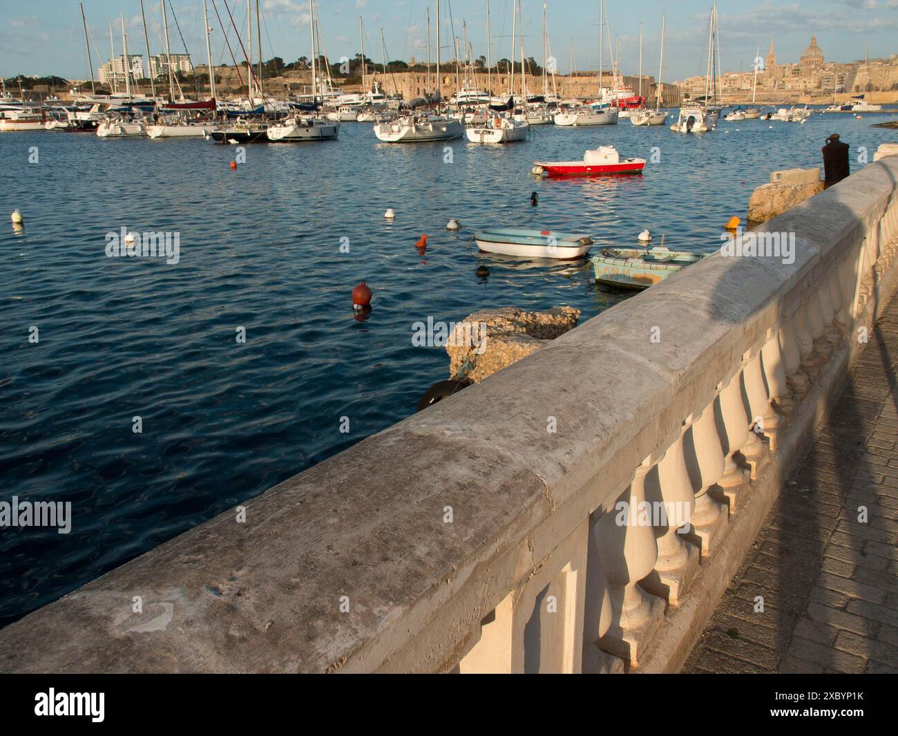 Balustrade en pierre le long de la rive du port avec de nombreux bateaux dans l'eau et la ville en arrière-plan, valette, mer méditerranée, malte Banque D'Images