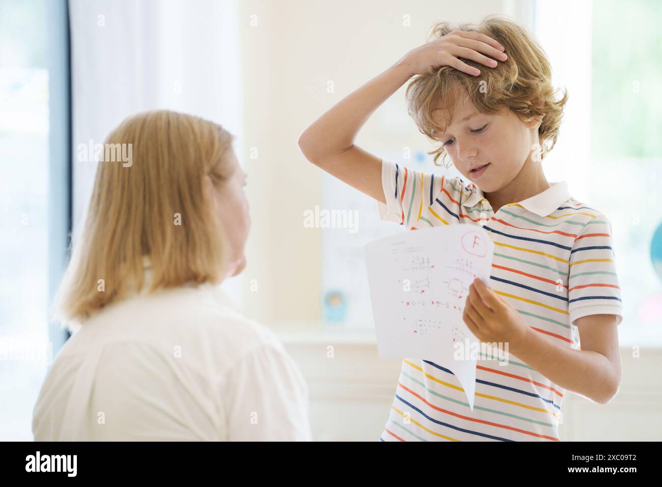 Enfant ayant un test scolaire avec une mauvaise note F. Étudiant contrarié après l'examen de mathématiques. Echec du test mathématique. Garçon stressé pleurant avec du papier de note raté dans le sien Banque D'Images