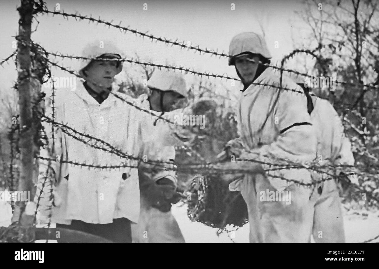 Photo de capture d'écran de la seconde Guerre mondiale B&W . Des soldats allemands habillés en camouflage des neiges installant un périmètre de barbelés sur le front russe en février 1943 Banque D'Images
