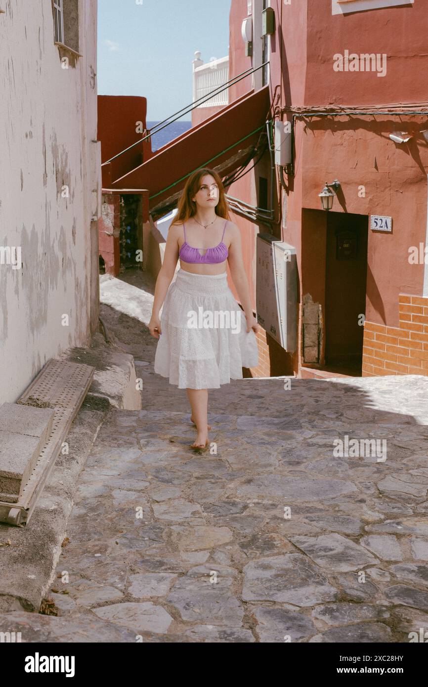 Une femme dans un haut violet et une jupe blanche marchant dans la rue Banque D'Images