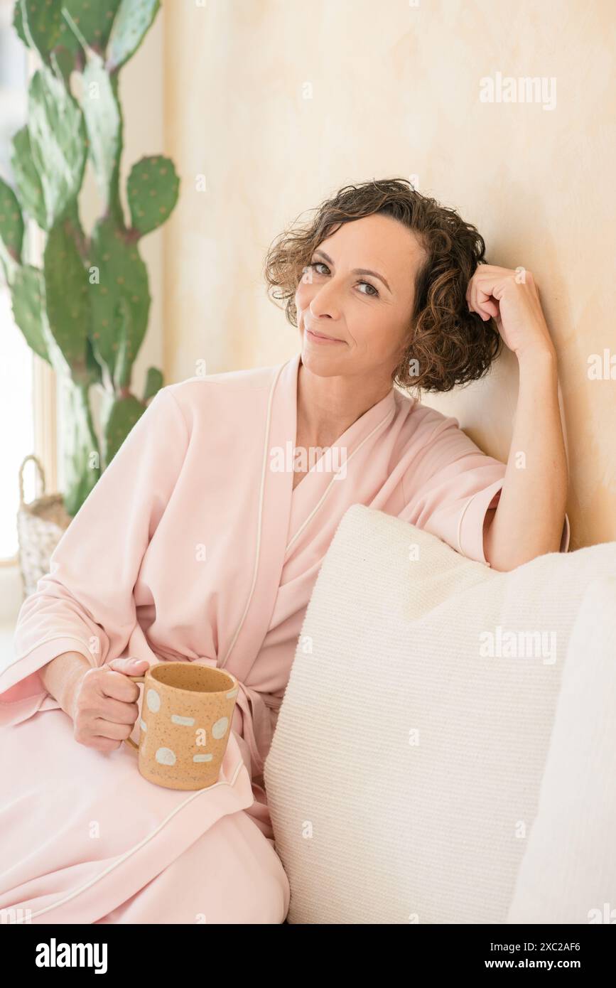 femmes se relaxant sur le canapé tenant la tasse dans la maison neutre Banque D'Images