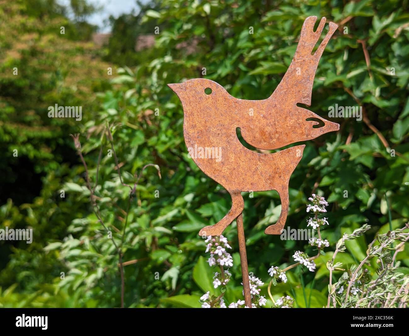 Jardin Metal Decor oiseau dans un jardin de printemps luxuriant Banque D'Images