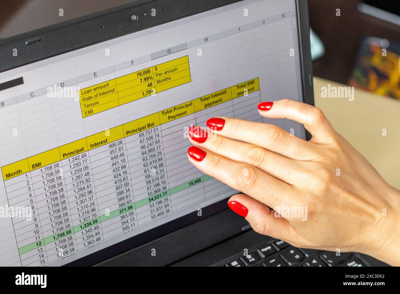 Gros plan de la femme avec de belles mains et manucure, travaillant sur l'ordinateur portable, écran tactile défilant avec table d'amortissement de prêt hypothécaire ouverte Banque D'Images