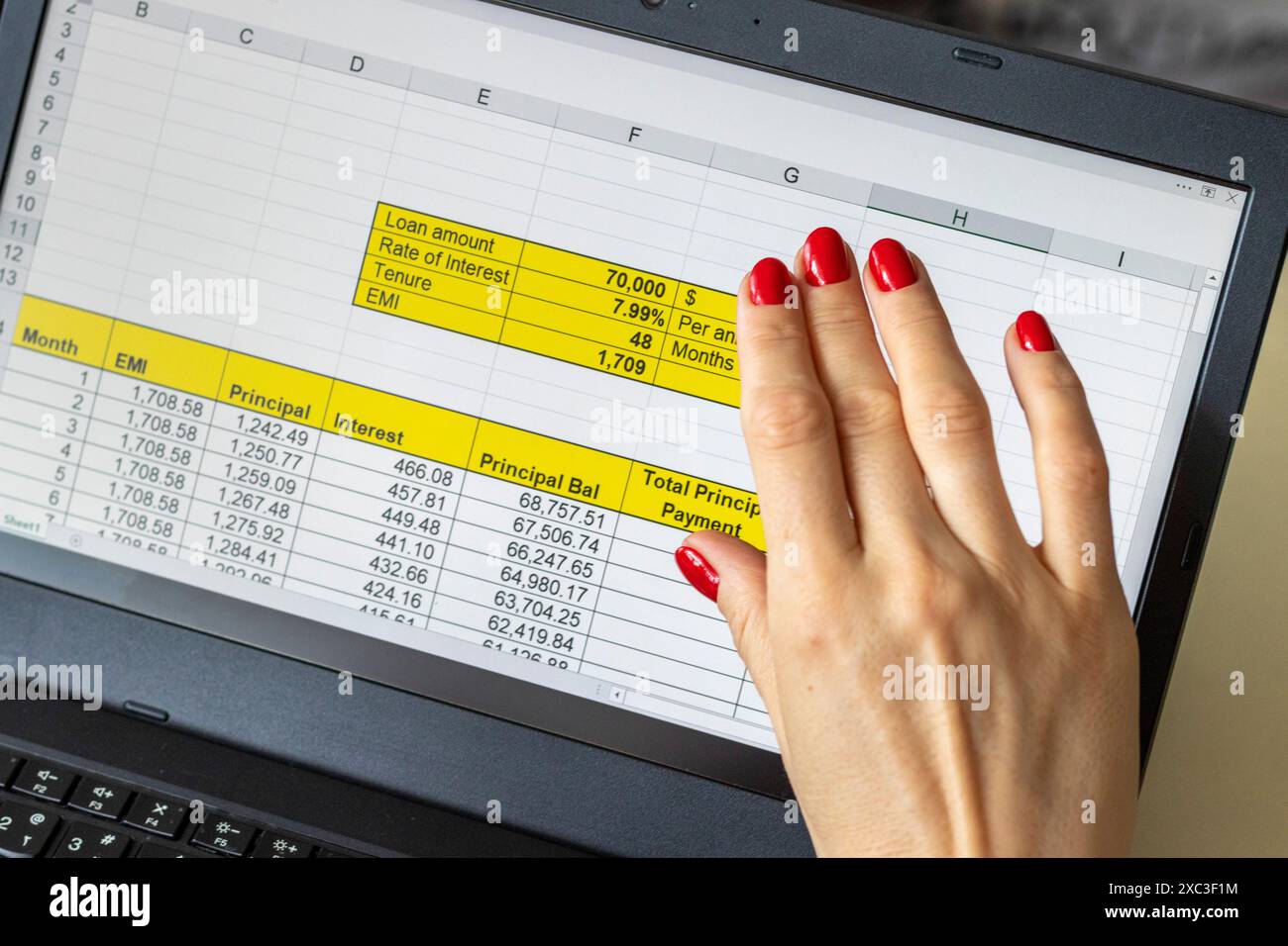 Gros plan de la femme avec de belles mains et manucure, travaillant sur l'ordinateur portable, écran tactile défilant avec table d'amortissement de prêt hypothécaire ouverte Banque D'Images