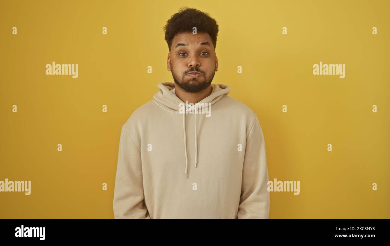 Portrait d'un bel homme afro-américain adulte portant un sweat à capuche sur fond jaune. Banque D'Images