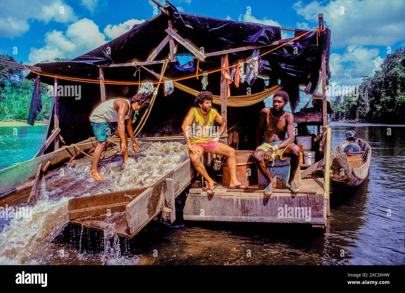 Suriname. Les travailleurs brésiliens cherchent de l'or dans la rivière Tapanahony. Ils tamisent la terre recueillie sur une «usine» flottante et l'or est extrait Banque D'Images