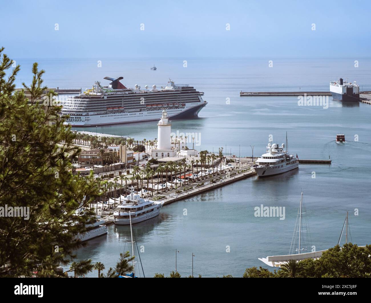 Le port portuaire de Malaga avec le phare de la Farola et de grands bateaux de croisière touristique ancrés, Andalousie, Espagne Banque D'Images