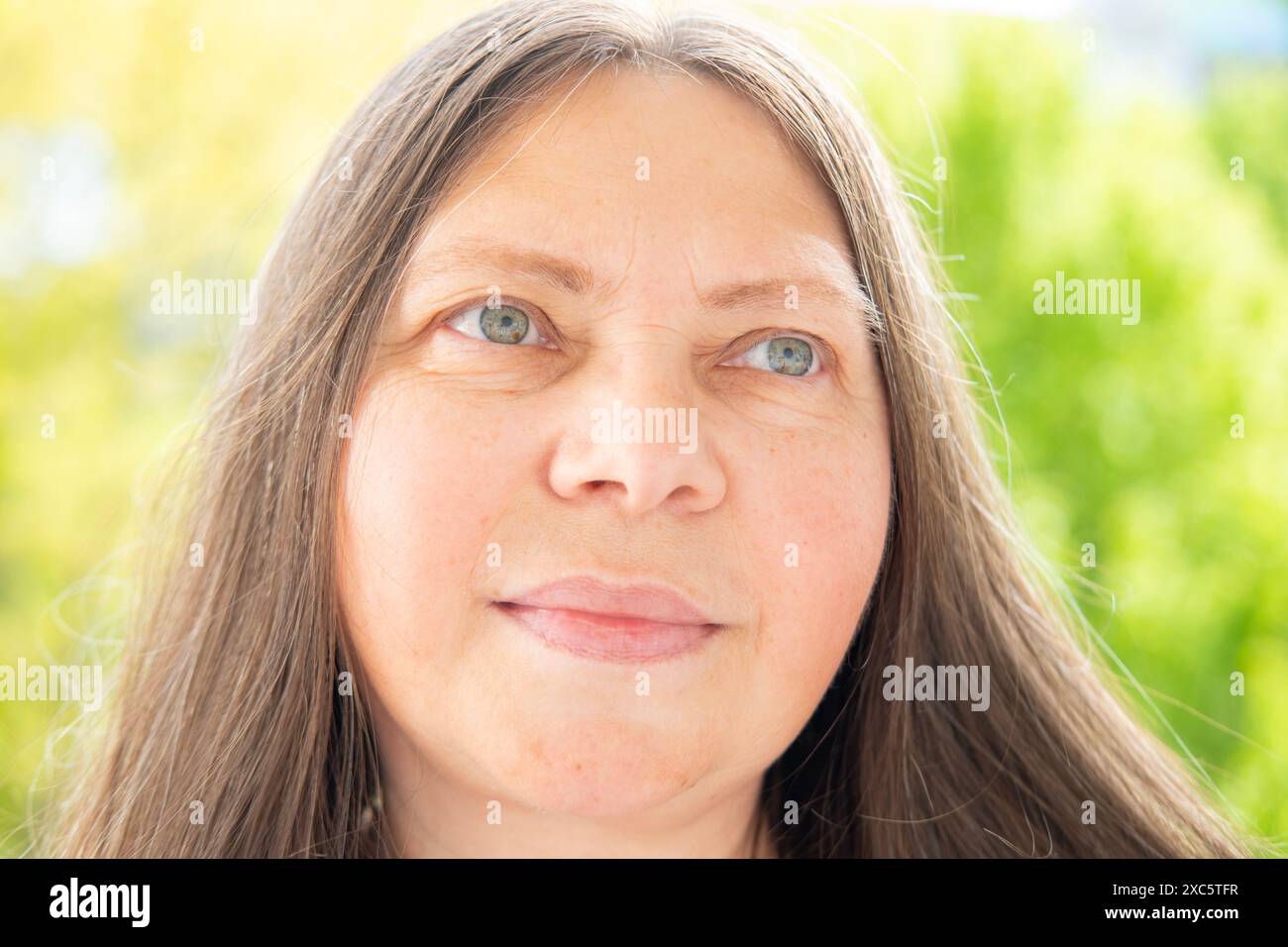 Caucasien positive 50 ans femme attrayante avec de longs cheveux pose gracieusement, joli visage gros plan portrait, soins anti-vieillissement procédures, la vie et e Banque D'Images