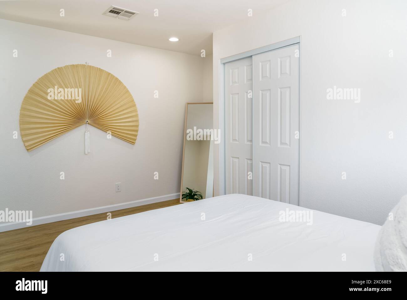 Intérieur de chambre bohème moderne blanc avec lit, ventilateur pliant art et miroir de sol désert maison Banque D'Images