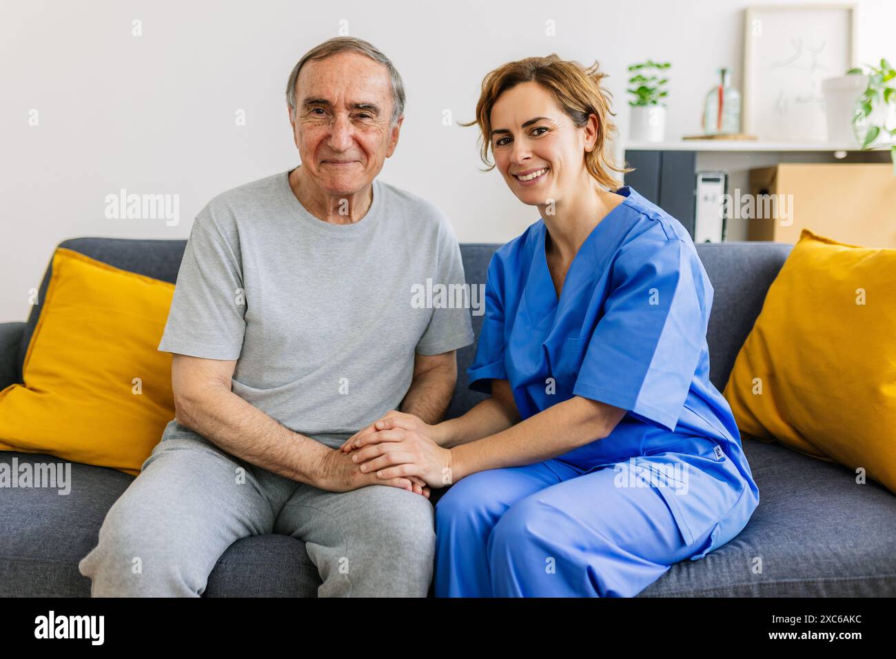 Portrait joyeux d'une soignante de mi-adulte avec un patient âgé à domicile Banque D'Images Portrait joyeux d'une soignante de mi-adulte avec un patient âgé à domicile Banque D'Images