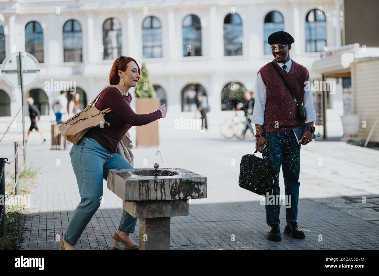 Rencontre d'affaires décontractée à une fontaine d'eau urbaine pendant une journée ensoleillée Banque D'Images