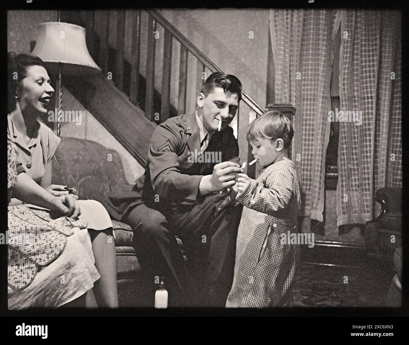 Papa de l'armée apprend à un tout-petit à fumer une cigarette. Image tirée d'un négatif 4x3 cm. Banque D'Images