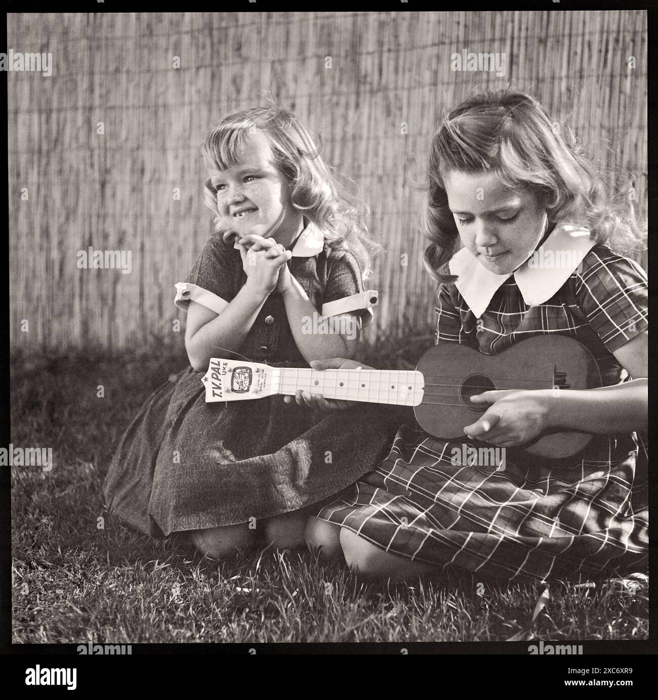 Deux jeunes filles jouant avec un ukulélé, années 1950 Image tirée d'un négatif 6x6cm. Banque D'Images