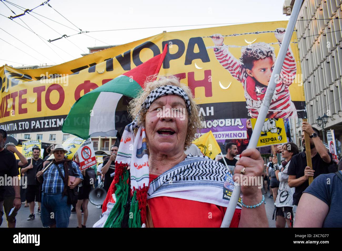 Athènes, Grèce. 14 juin 2024. Un manifestant tient un drapeau palestinien lors d'une manifestation pour marquer un an après l'une des pires tragédies de bateaux de migrants. Les agences des Nations Unies pour les réfugiés et les migrations critiquent l'incapacité de la Grèce à faire la lumière sur le naufrage de migrants. Le 14 juin 2023, l'Adriana, un bateau rouillé transportant clandestinement jusqu'à 750 migrants de Libye vers l'Italie, a coulé, tuant des centaines de personnes en présence des garde-côtes helléniques. Crédit : Dimitris Aspiotis/Alamy Live News Banque D'Images