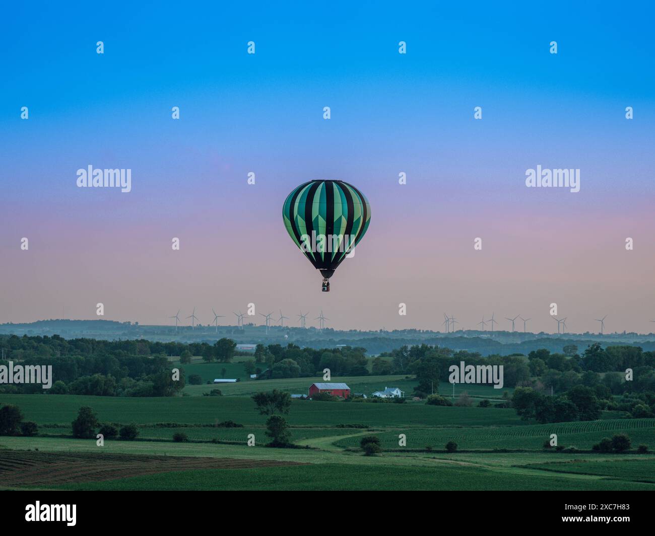 Monroe, Wisconsin, États-Unis. 14 juin 2024. Une montgolfière commence sa descente finale dans les collines ondulantes du comté de Green au Wisconsin au crépuscule, après un lancement réussi de la première nuit du Monroe Balloon and Blues Festival. (Crédit image : © Ross Harried/ZUMA Press Wire) USAGE ÉDITORIAL SEULEMENT! Non destiné à UN USAGE commercial ! Banque D'Images