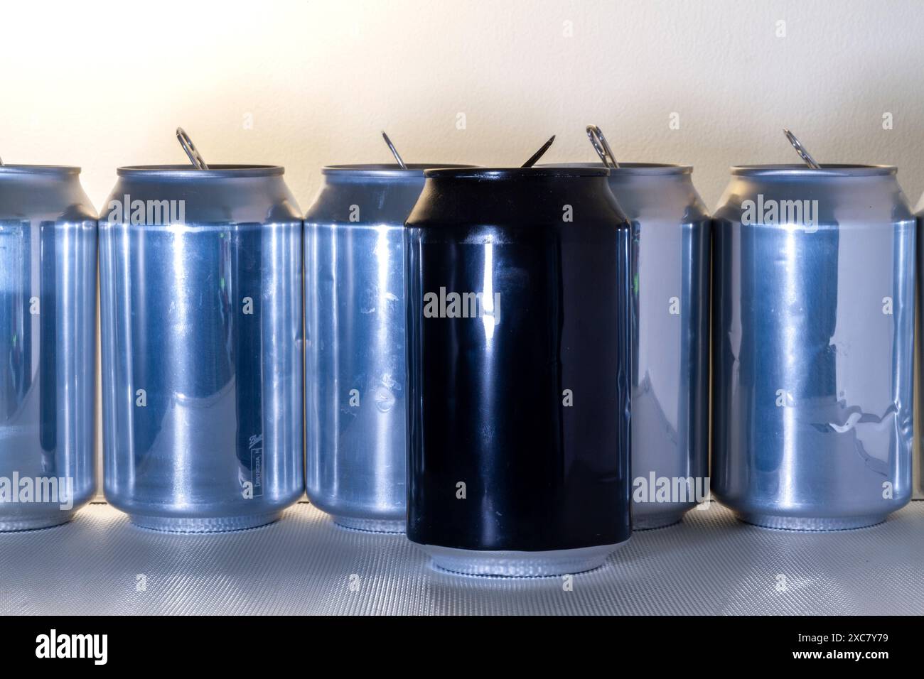 Une canette en aluminium Balck se trouve devant une ligne de canettes argentées Banque D'Images