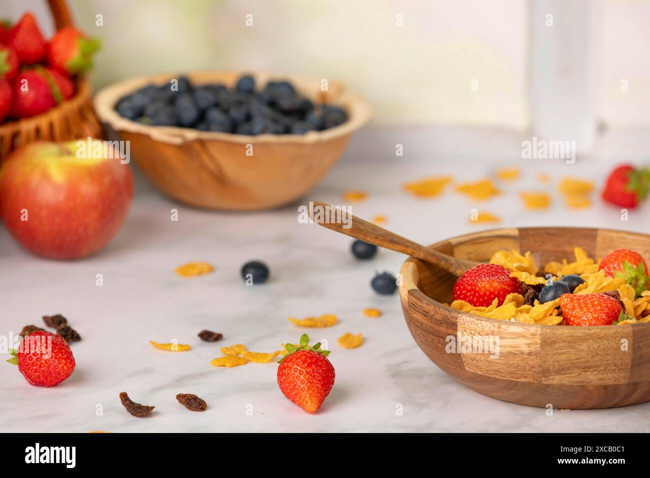 Gros plan d'un bol de céréales rempli entouré d'ingrédients, pomme, fraises, bleuets et cornflakes Banque D'Images Gros plan d'un bol de céréales rempli entouré d'ingrédients, pomme, fraises, bleuets et cornflakes Banque D'Images