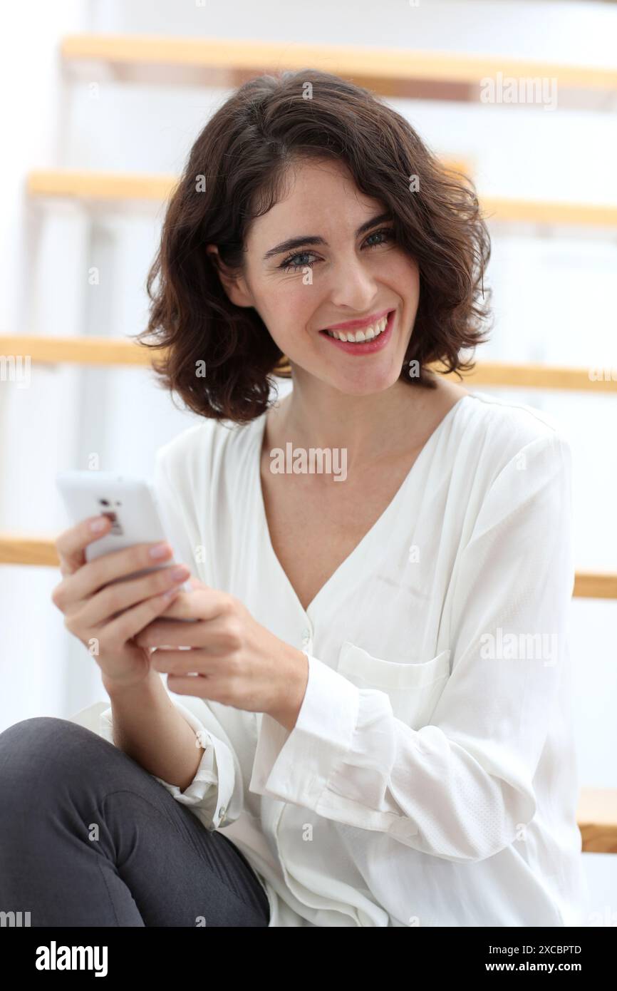 Femme assise sur un escalier et à l'aide de smart phone Banque D'Images