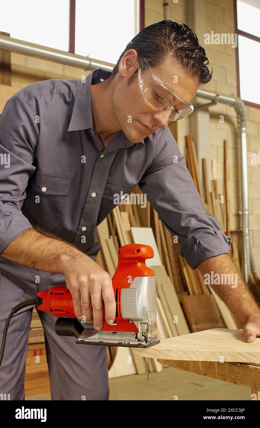 Carpenter cutting la planche en bois chantourner avec Banque D'Images