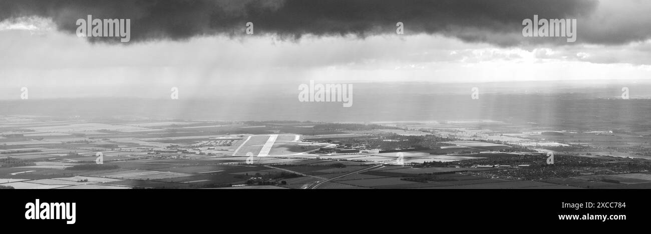 Photo aérienne de la RAF Waddington dans la distance prise à 1500 pieds avec des nuages orageux noirs au-dessus de la tête et des rayons du soleil Banque D'Images