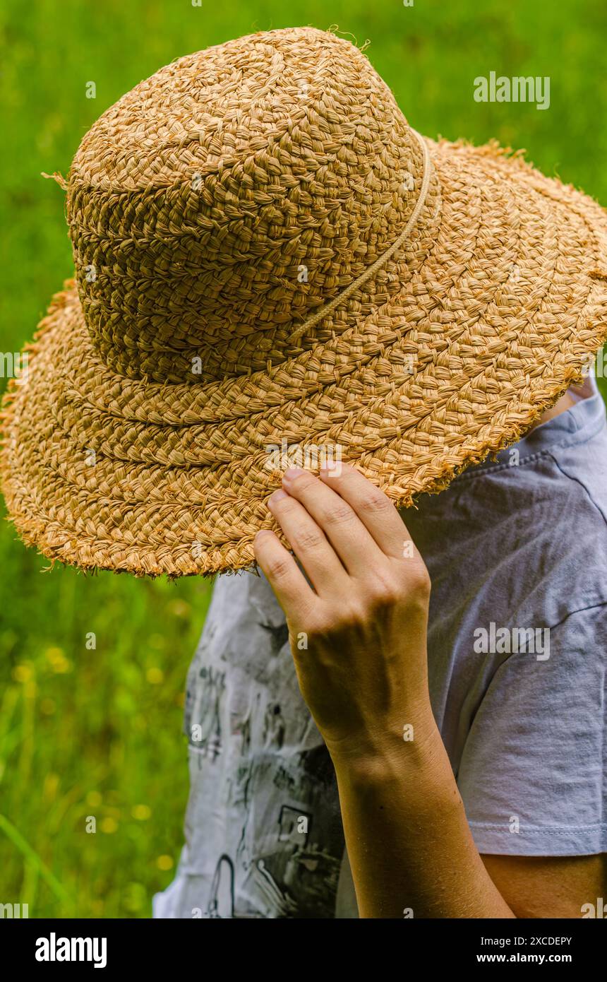 Femme en chemise blanche tenir le chapeau en bois couvert visage en flou naturel. Photo de haute qualité Banque D'Images