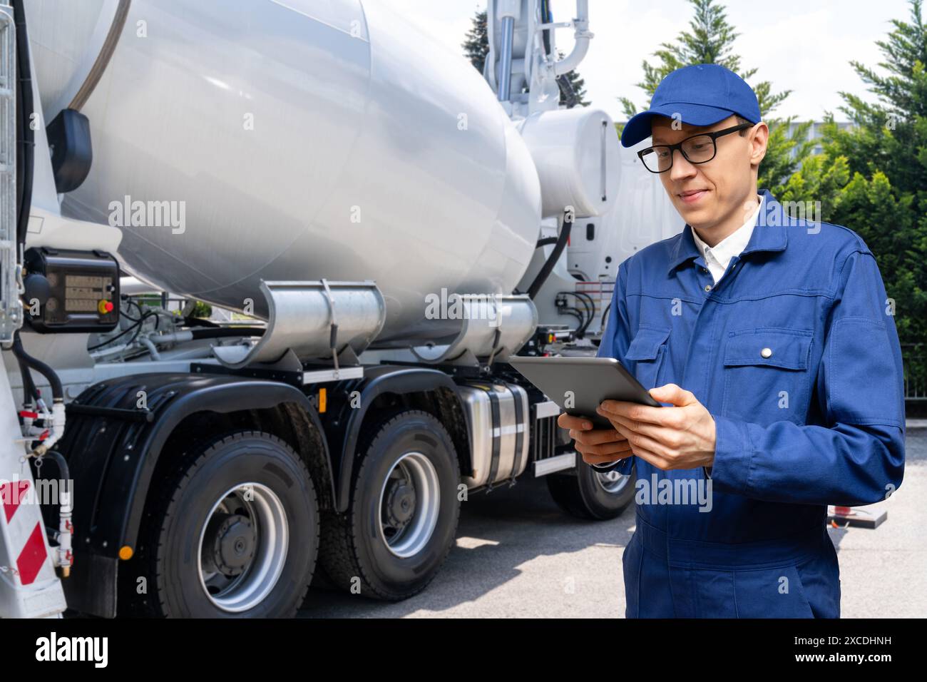 Travailleur avec tablette numérique à côté de la pompe à béton montée sur camion avec mélangeur.. Banque D'Images