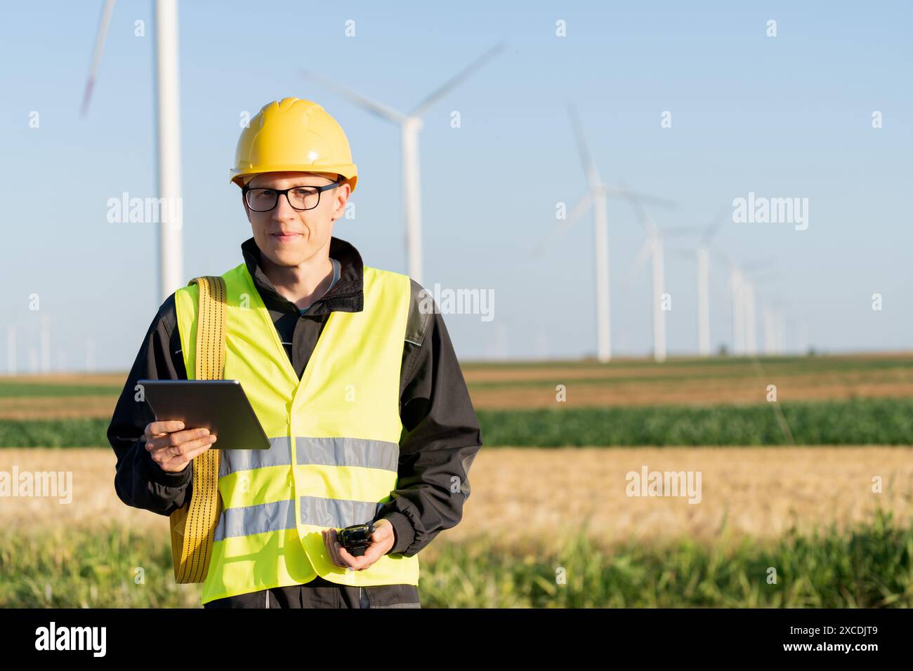 Ingénieur avec tablette numérique travaille sur un champ d'éoliennes. Banque D'Images