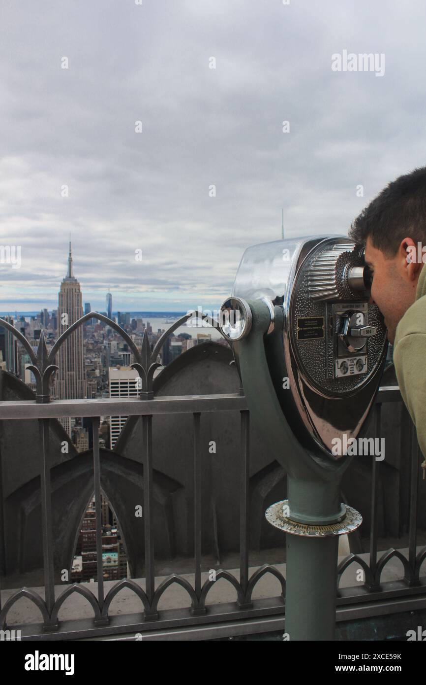 15/03/2022, New York, Man regarde l'emblématique Empire State Building à l'aide de jumelles depuis la terrasse d'observation Top of the Rock. Cette image capture un Banque D'Images