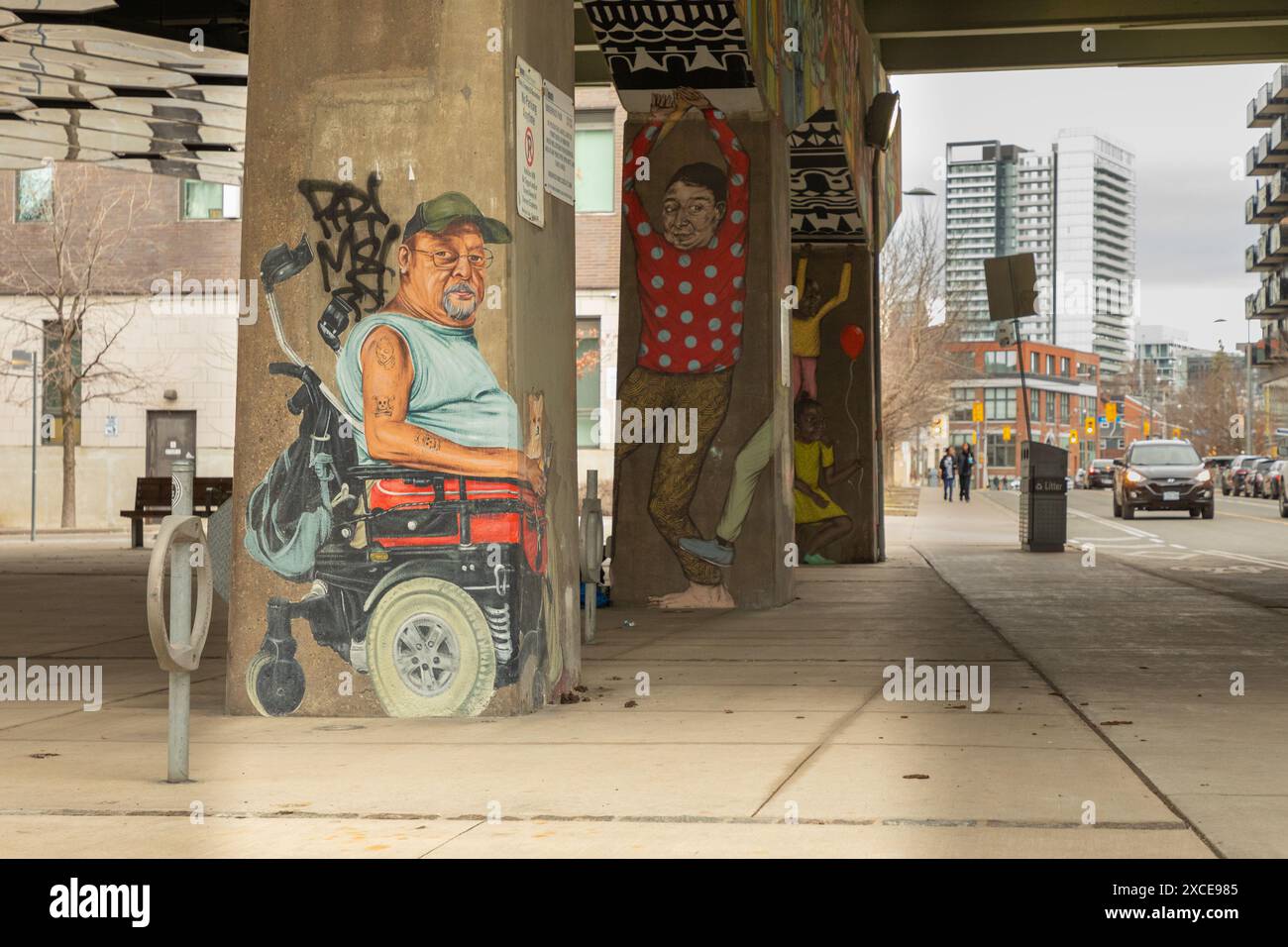 Une murale frappante représentant un homme en fauteuil roulant motorisé, peinte sur le support en béton d’une autoroute aérienne, attire l’œil des passants. Banque D'Images