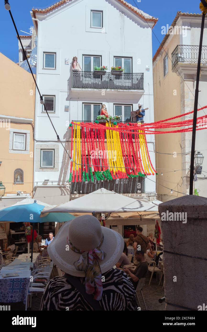 Touriste dans la rue Alfama à Lisbonne, Portugal, pendant les festivités populaires des Saints, regardant un bâtiment avec des décorations colorées typiques Banque D'Images