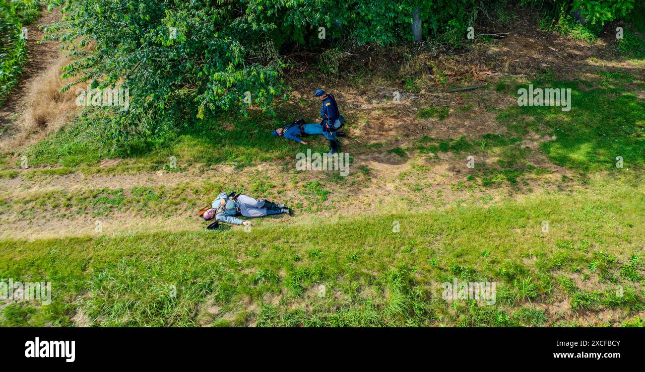 Ronks, Pennsylvanie, États-Unis, 8 juin 2024 - les reconstituteurs de la guerre de Sécession en uniformes bleu et gris reposent sur l'herbe, dépeignant Une scène de bataille avec des soldats tombés près d'Une zone boisée, avec une garde permanente, sur fond verdoyant. Banque D'Images