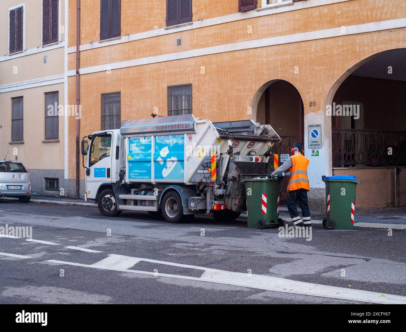 Cremona, Italie - 10 juin 2024 collecteur de déchets municipaux en uniforme vidant les poubelles dans la rue avec un camion à ordures Banque D'Images