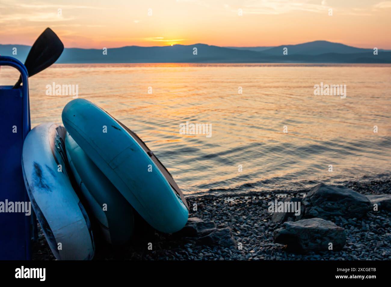 SUP planches sur la rive d'un lac pittoresque avec pour toile de fond le lever du soleil Banque D'Images