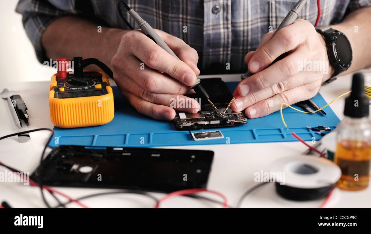 Le technicien principal d'un centre de réparation de matériel électronique est en train de réparer Un téléphone intelligent et de démonter le téléphone Banque D'Images