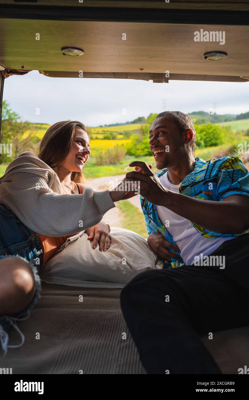 Heureux couple diversifié couché dans la camionnette et passant du temps ensemble Banque D'Images