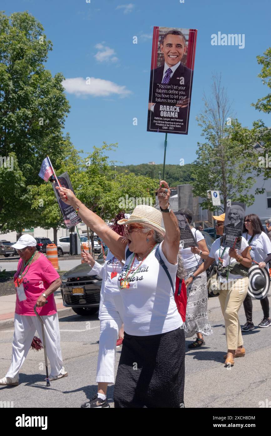 Un membre du Peekskill Seniors Club marche lors de la parade de la quinzième année avec un drapeau et une photo du président Obama. Dans Peekskill, juin 2024. Banque D'Images