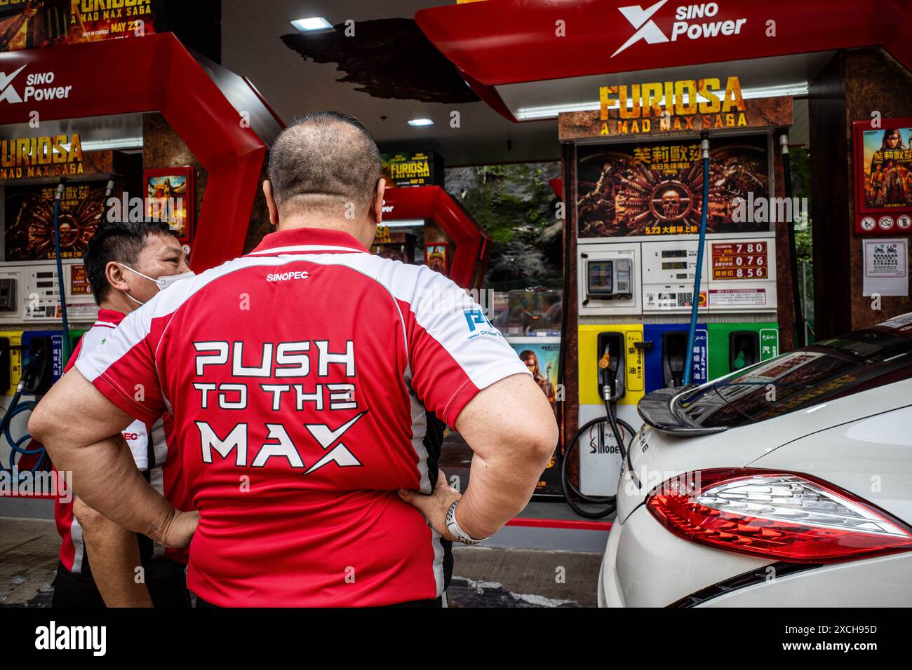 Hong Kong, Chine. 9 juin 2024. Deux préposés conversent à une station-service de Quarry Bay, entourés par un lien promotionnel entre SINOPEC et Warner Bros Pour Furiosa : a Mad Max Saga, basé sur une histoire post-apocalyptique où l’essence est une ressource finie et où les tyrans combattent dans les terres usées à l’aide de véhicules moddés, le Tie-in est une stratégie marketing unique pour les deux parties. (Crédit image : © Ben Marans/SOPA images via ZUMA Press Wire) USAGE ÉDITORIAL SEULEMENT! Non destiné à UN USAGE commercial ! Banque D'Images