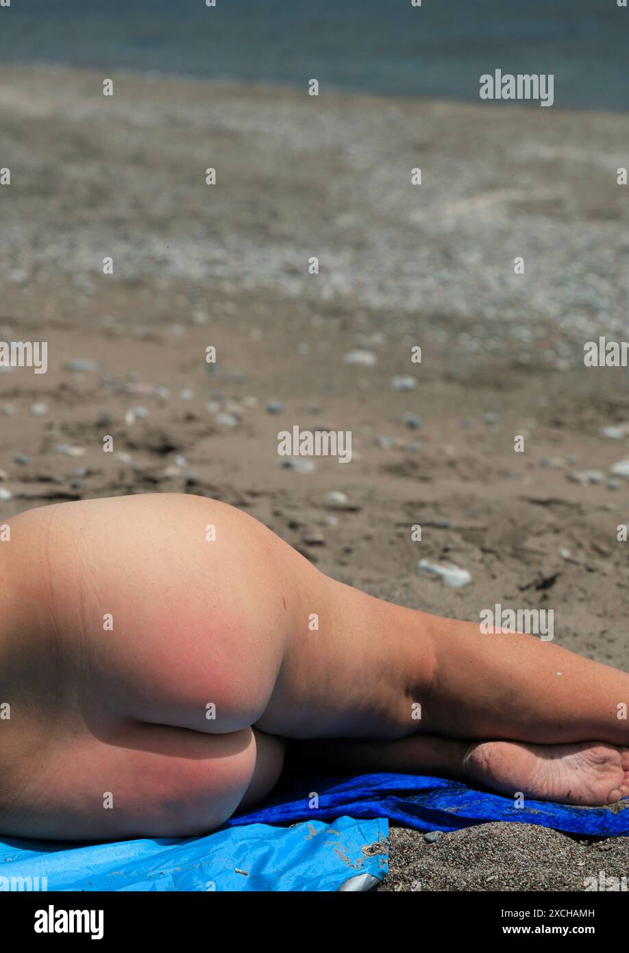 Femme nue profitant du temps sur la plage, îles du Dodécanèse, sud de la mer Égée, Grèce. Banque D'Images