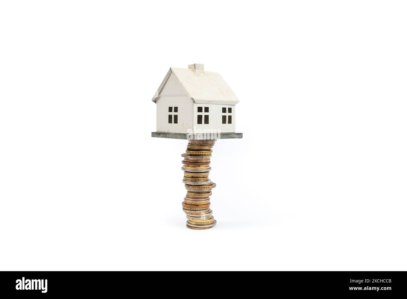 Maison miniature en métal debout sur une haute pile de pièces d'or, isolée sur fond blanc Banque D'Images Maison miniature en métal debout sur une haute pile de pièces d'or, isolée sur fond blanc Banque D'Images