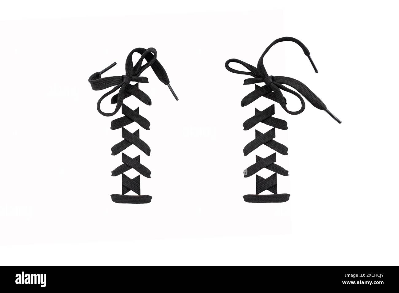 Paire de lacets de chaussures noirs noués avec un noeud dans un motif classique, isolé sur blanc, magasin de chaussures abstrait Banque D'Images