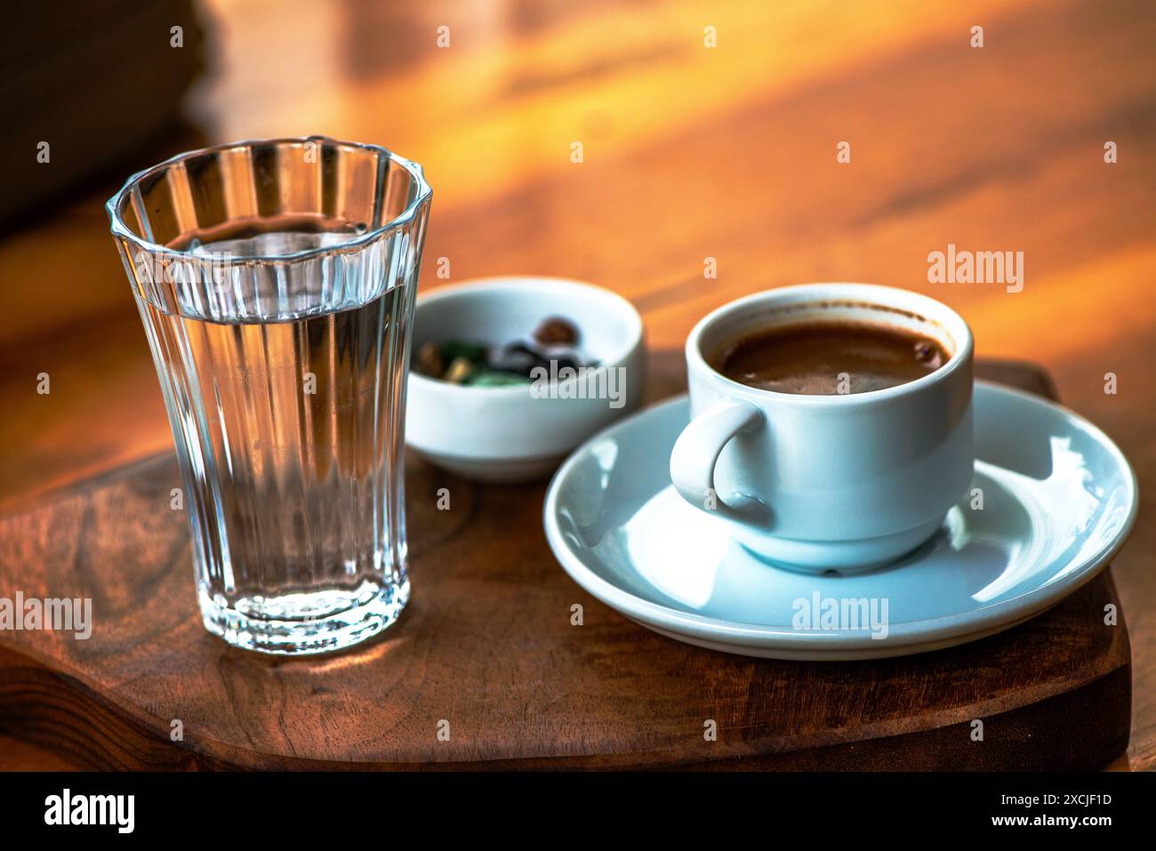 Présentation de café turc avec du chocolat aux galets et un verre d'eau, mettant en valeur une configuration traditionnelle et élégante sur la table. Banque D'Images