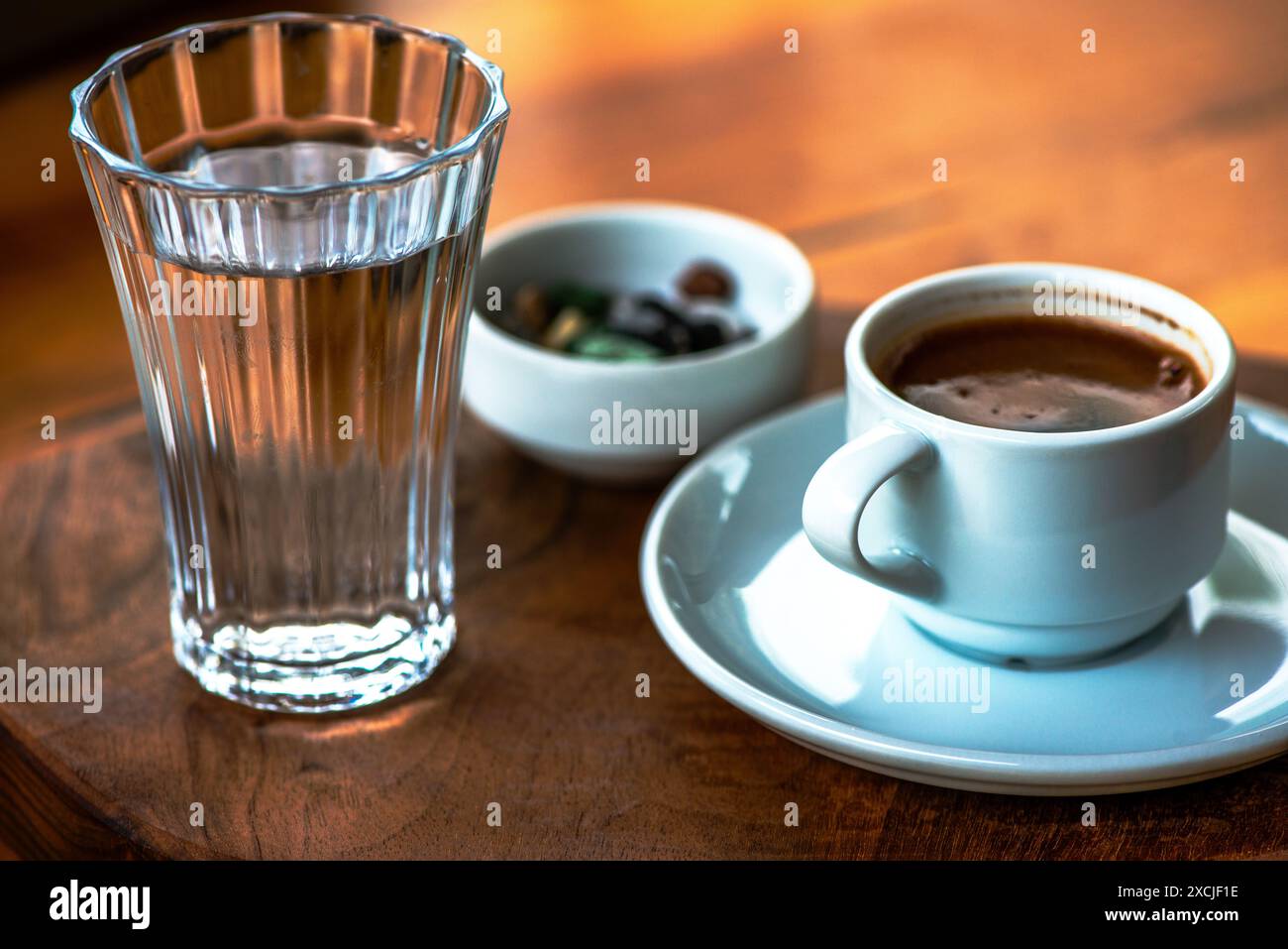 Présentation de café turc avec du chocolat aux galets et un verre d'eau, mettant en valeur une configuration traditionnelle et élégante sur la table. Banque D'Images