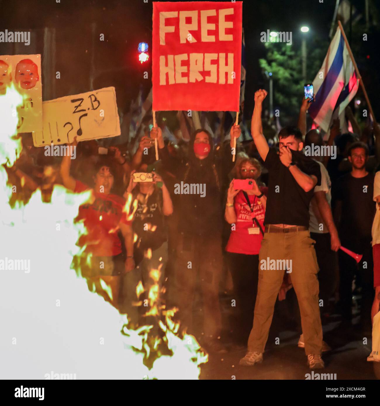 Jérusalem, Israël. 17 juin 2024 participants à une manifestation antigouvernementale près de la maison privée du premier ministre israélien (Netanyahu) à Jérusalem. Les manifestants appelaient à de nouvelles élections et à la libération des otages grâce à un accord entre Israël et le Hamas. Les manifestants lèvent des pancartes. Devant eux se trouve un feu de joie. En arrière-plan, il y a des drapeaux israéliens. Crédit : Yoram Biberman/Alamy Live News. Banque D'Images